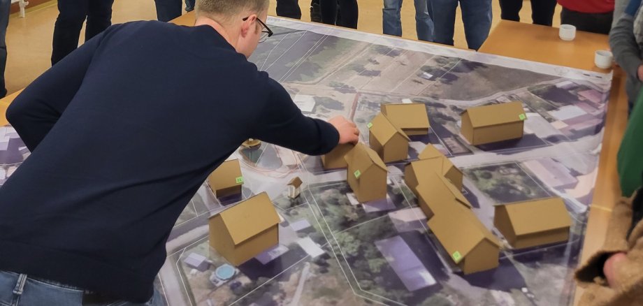 Eine Person beugt sich über einen städtebaulichen Plan von Hommershausen