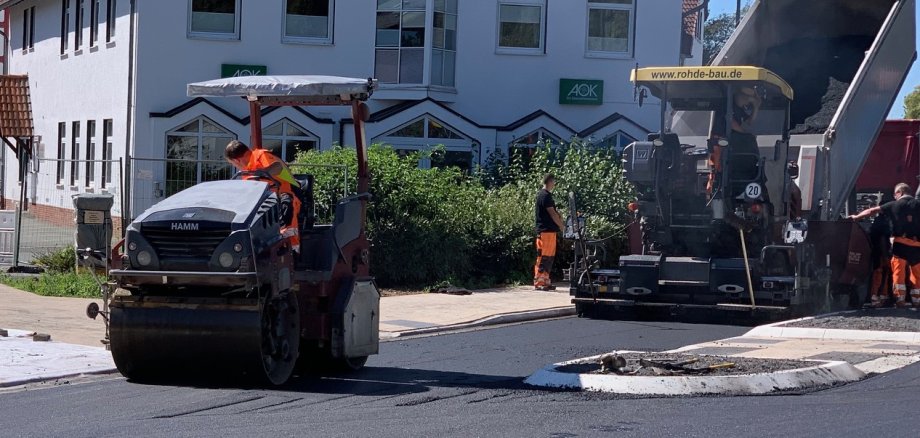 Baufahrzeuge auf einer frisch asphaltierten Straße